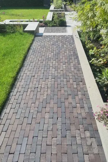 Long path of Lugano Dutch Clay Pavers with flowerbed on one side and large lawn on the other, stepping down to more flowerbeds.