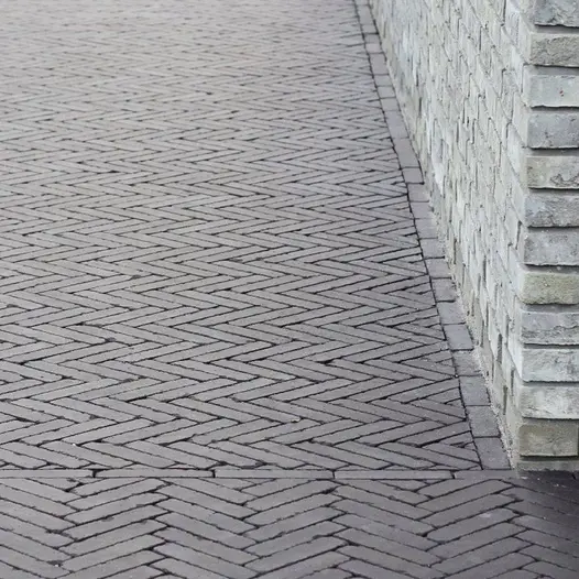 Zoomed in shot of large area of paving using amersham clay pavers in unique designs, set against a light brick wall.