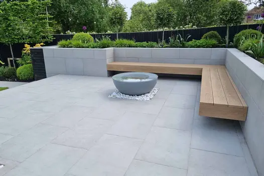 Floating bench above polished concrete porcelain paving around firepit with raised walls used for flowerbeds.