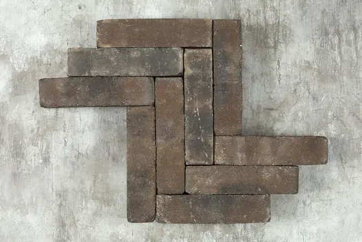 10 Ancona clay pavers laid edge-on in herringbone pattern against grey cement background. Free UK delivery available.