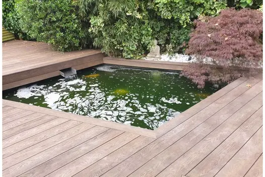 Sunken goldfish pond surrounded by Antique Oak Enhanced Grain Millboard. Water fills it through spout set into decking fascia.