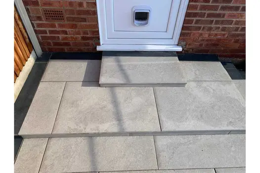 Door with cat flap above 2 steps in Astor Grey porcelain slabs and Charcoal plank paving. Built by C and C Agricultural Services.