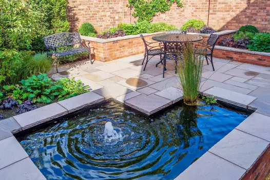 Bubble fountain in L-shaped brick-sided raised pond edged with Autumn Brown sandstone coping to match surrounding patio.