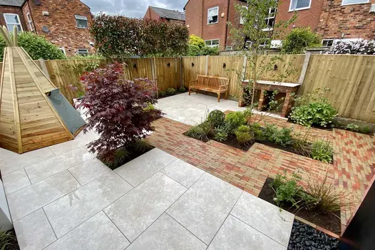 Wood tepee in fenced garden paved with cream porcelain and mix of Seville and Westminster Clay Pavers. Built by Bark Brick & Block.