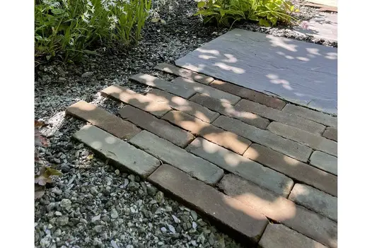 Bergamo Dutch Clay Pavers laid running bond with gravel and paving slabs next to planted border. Built by Big Fish Landscapes.