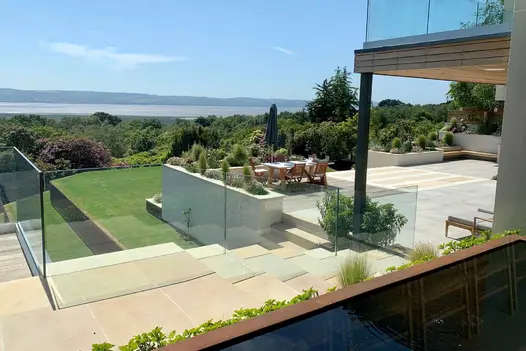 View to wide river across treetops and multi-level patio of Harvest Sawn sandstone with steps and glass railings.