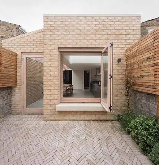 Backyard laid with Westminster Clay Pavers with view into modern kitchen through open window from. Design by Oliver Leech.