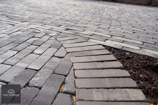 Meeting of 2 Lucca brick paving paths laid with pavers in 2 directions, with curved soldier course. Design by Karl Harrison.