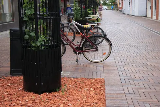 Pedestrianised lane laid with red and brown Bromley Clay Pavers. Bicycles parked between metal plant towers.
