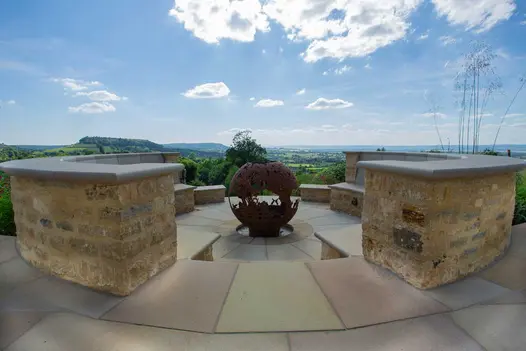 Decorative fire bowl in centre of sunken seating circle, bench seats topped with bespoke Buff Sawn Sandstone bullnose step treads.
