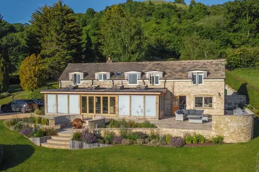 View of house with wide patio, sunken seating area and curved sawn buff sandstone bullnose steps down to enormous lawn. 