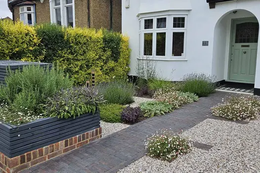 Front of house shot showing path of ancona clay pavers with insets to create flowerbeds, surrounded by pebbles.