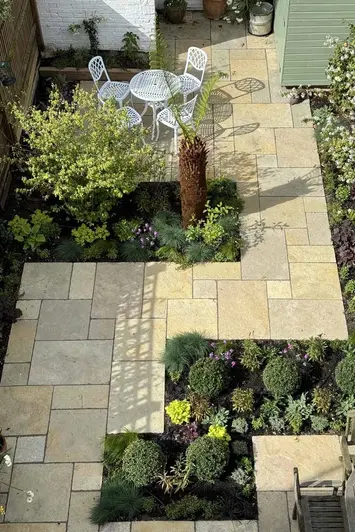 Birds eye view of Z-shaped garden design using Antique yellow Limestone Paving, shrubs and trees inbetween with dining area at the back.