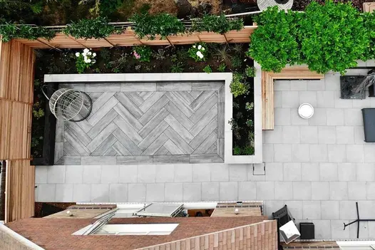Overhead view of paved back garden. Cinder wood-effect planks edged by rectilinear raised bed and Cement porcelain tiles.