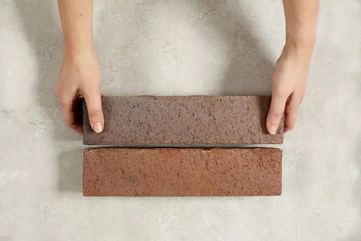 2 well-mainicured hands place one long Bromley clay paving brick against another on pale surface. Free UK delivery available.