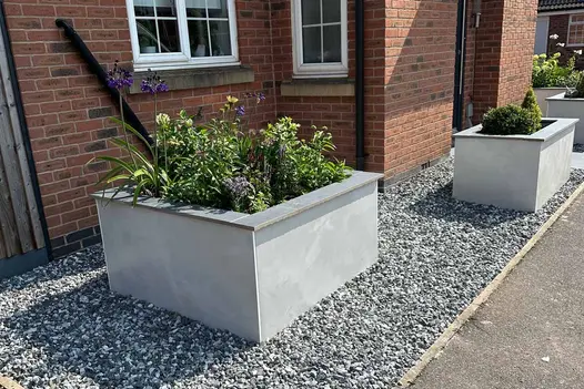 Close up side view of valencia white compact designclad cladding a raised flowerbed with porcelain coping.