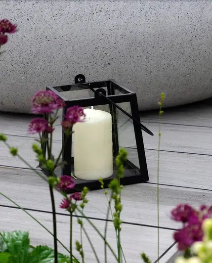 Close-up shot through purple flowers show a candle lantern sitting on luna designboard composite decking.