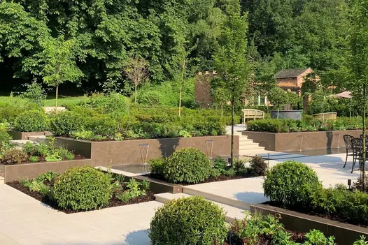 Very large multi-level garden surrounded by trees, with terraced beds faced in Dark Mocha exterior cladding. Design by Botanica.
