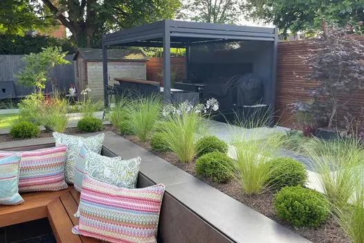 Pergola in distance with Dark Mocha exterior cladding used to create enclosed firepit with floating bench.