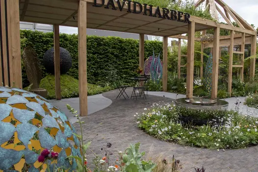 Sinuous stretch of Lucca brick paving runs across David Harber RHS Chelsea trade stand between round planted bed and sculpture.