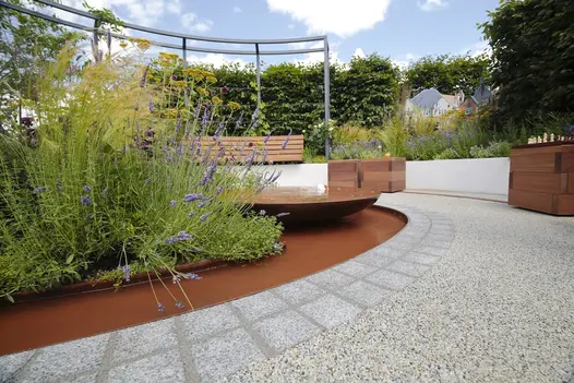 2 rows of sawn silver grey granite setts create edge between resin-bonded gravel and curved pond with water bowl and planting.