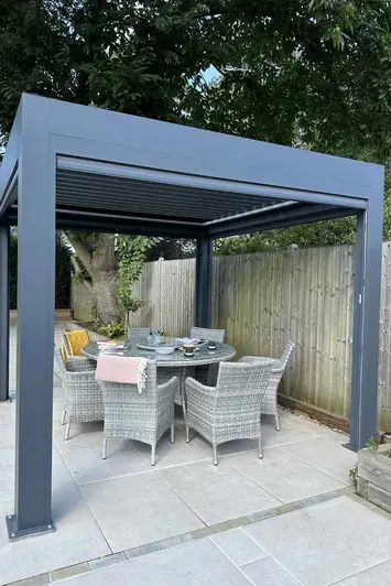 Close-up view of a dining area under the Anthracite Grey 3x3 Deluxe Pergola, highlighting the alfresco dining experience in the shade.