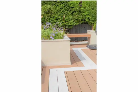 Raised beds faced with Desert Beige Premium DesignClad exterior cladding, and filled with airy planting, next to composite decking.