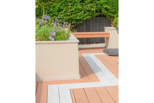 Strip of polar designboard runs through mocha decking next to raised flowerbeds and built in bench.