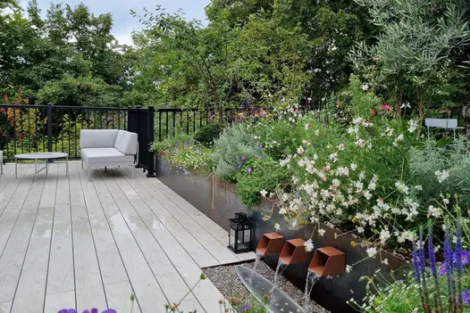 Wet Luna DesignBoard light grey composite decking with modular sofa, water feature with 3 spouts and planting by Adam Vetere.