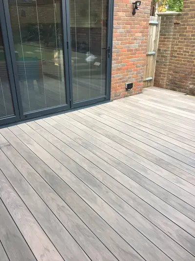 Close up view of Traditional Designboard Composite Decking used outside black french doors on red brick house.