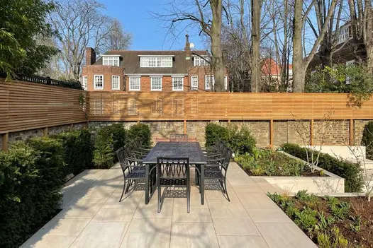 Faro Porcelain raised patio next to garden walls, accessed by Faro Simple Garden Steps, with metal dining table and 10 chairs.