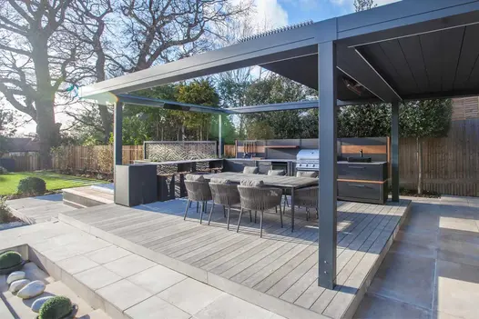 Florence Grey Porcelain Paving surrounds decking under large metal pergola. Design by Simon Orchard. Built by Graduate Landscapes.