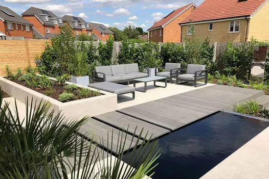 Garden by Limebok Landscaping, paved in Florence Grey Porcelain and Pebble Grey DesignBoard, with oblong pond and luxury furniture.