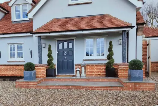 Wet Florence Storm Porcelain Paving, accompanied by paving steps, guides to the front door, flanked by topiary planting on both sides.