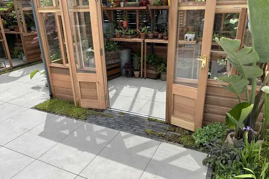 Timber framed glass house sat on top of a Porcelain paved base with a charcoal coloured Clay Paver entry threshold.