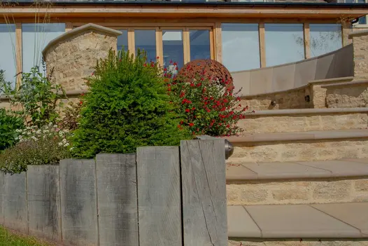 Garden steps ideas of Buff sandstone bullnose treads with brick risers ascending to patio with curved stone seating.