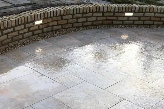 Curved area of wet paving bordered by Mint Sandstone Walling 4 bricks high with bricks laid on edge as capping. Lights set into wall.