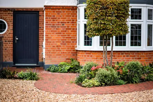 Red, grey and brown Winton clay pavers in curved approach to side gate of brick house, with inset beds. Design by Georgia Lindsay.