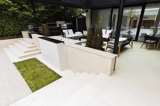2 sets of white steps descend from covered patio on either side of wall faced with Off White Designclad exterior cladding.