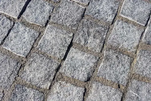 Zoomed in on natural black granite setts show riven texture, grouted with sand . Design by Greenbird Gardening.
