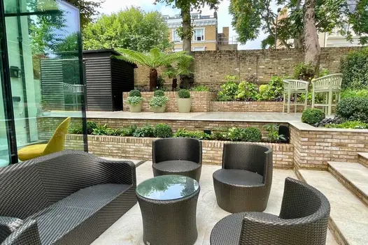 High-walled garden on 2 levels. Porcelain steps and paving with retaining walls and risers of London Mixture facing bricks.