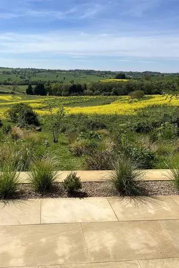 Harvest sawn sandstone paving used as patio paving with flowerbed insets lead off to impressive countryside views