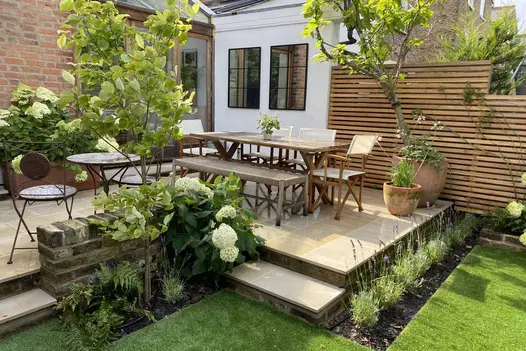 Dining set on L-shaped Harvest sawn sandstone patio with 2 sets of 2 steps down to lawn. 
