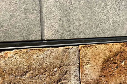 Slot drain seen in the middle of Astor Grey Porcelain Paving and belgian clay pavers, showing colour variations and texture.
