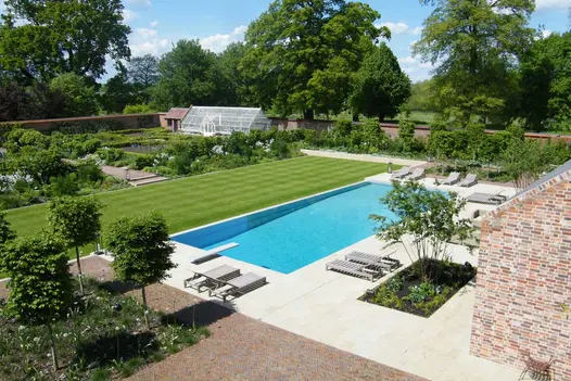 Large walled garden with formal vegetable patch, wide strip of lawn, and swimming pool set into Harvest Sawn sandstone patio.