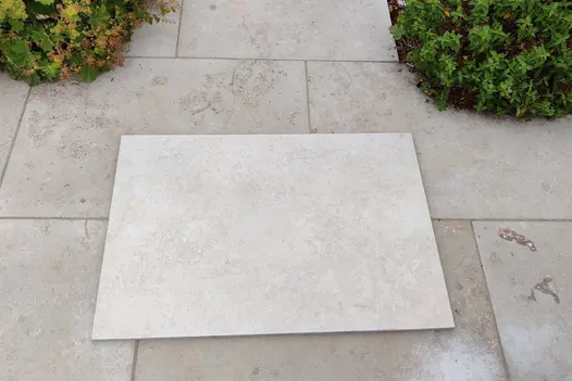 900x600 Jura Beige porcelain slab sitting on top of a real Jura Limestone stone patio to demonstrate the difference between porcelain and natural stone. 