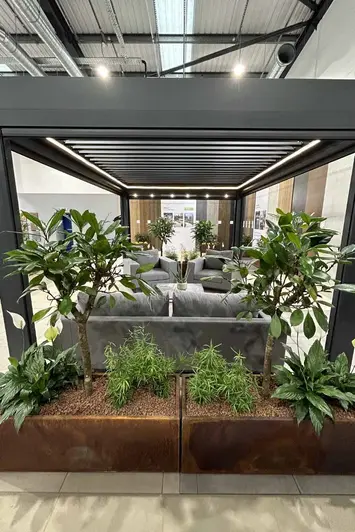 Pergola with partially closed roof louvres, which can provide filtered sunlight for an outdoor lounge area, installed in showroom.