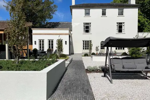 Lucca brick paving path runs between raised beds and gravelled area with swing seat to steps to patio by Pebble Landscape Design.