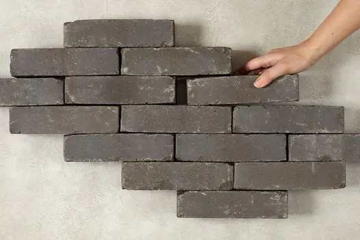 Hand places a Lugano Clay Paver into formation of 14 other bricks arranged in rows of 1, 2 and 3. Free UK delivery available.