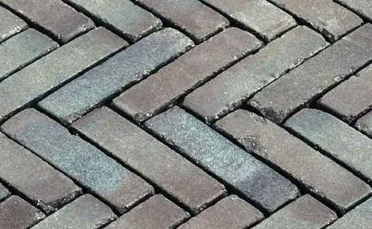 Close view of wet Lugano Dutch clay pavers laid herringbone, showing muted red and grey tones. Free UK delivery available.